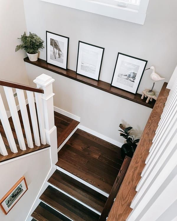 stairs leading up to the second floor with pictures on the wall above them and potted plants