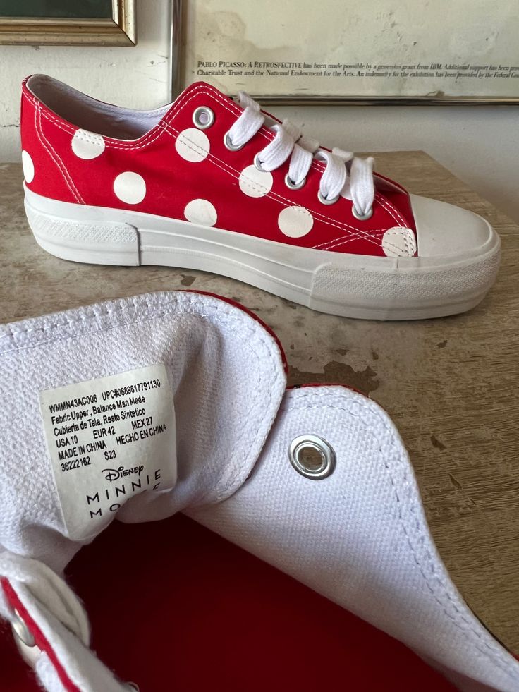 a pair of red and white polka dot tennis shoes with price tags on them sitting on a table