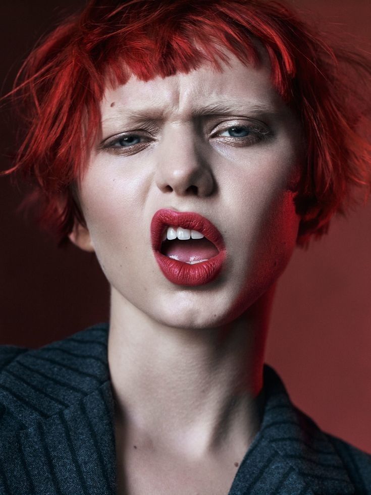 a woman with red hair is making a face and has her tongue out to the side