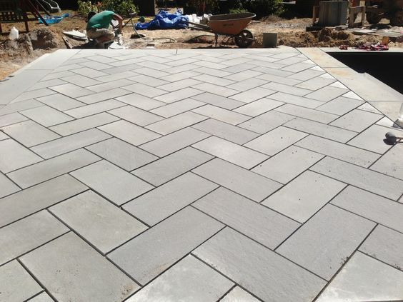 a bird is standing on the edge of a large brick patio that's being built