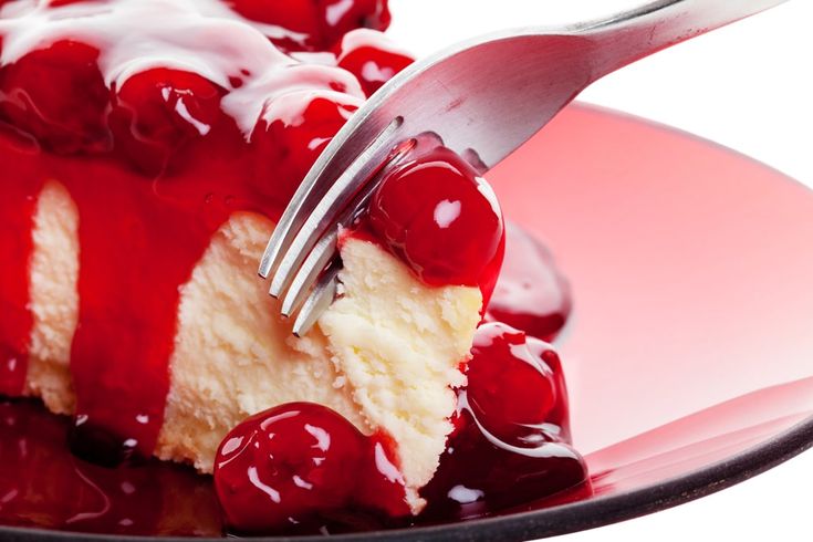 a piece of cheesecake with cherry sauce and a fork