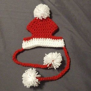 a red and white crocheted hat with pom - poms on it