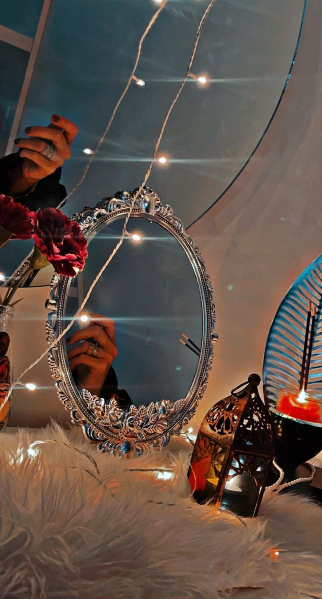 a person is taking a photo in a mirror with candles and flowers on the table