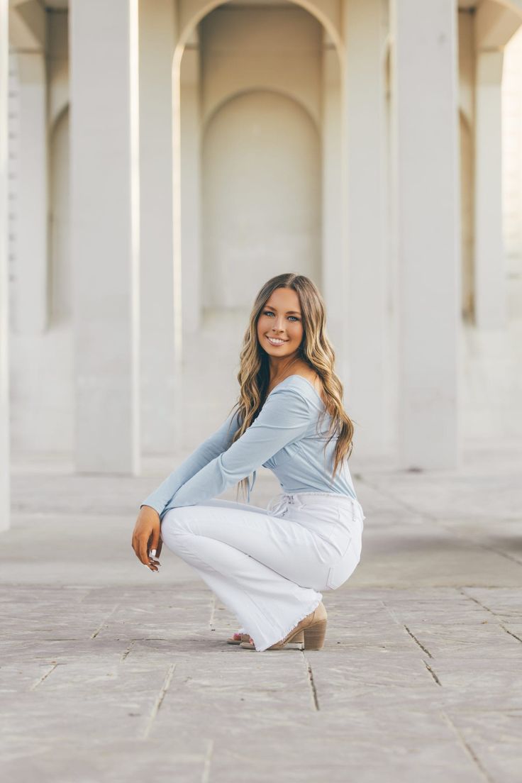 a woman kneeling down on the ground in front of an archway with columns and pillars