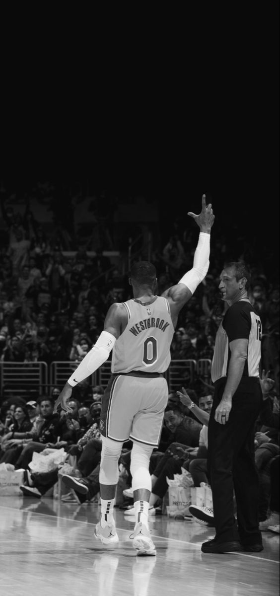 an old photo of a basketball player on the court with his arms in the air