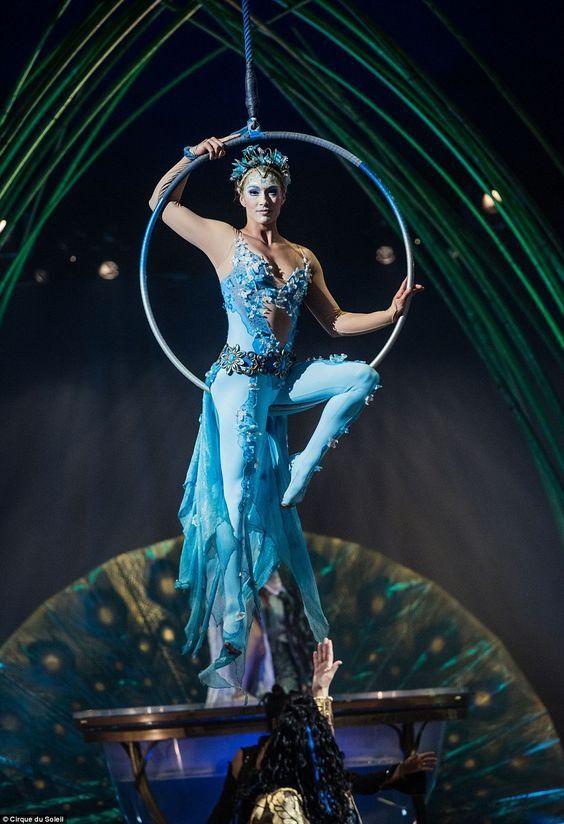 a woman in a blue dress is balancing on a hoop