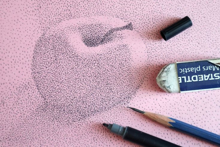 two pencils and a eraser on a pink surface with a drawing of a man's head