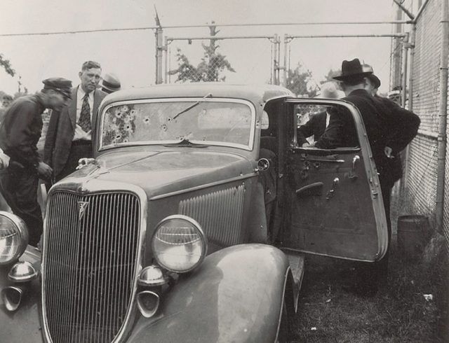 an old black and white photo of men standing next to a car