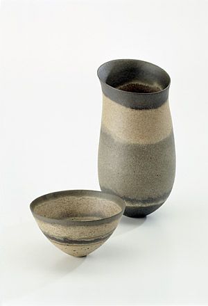 two black and grey vases sitting next to each other on a white table top