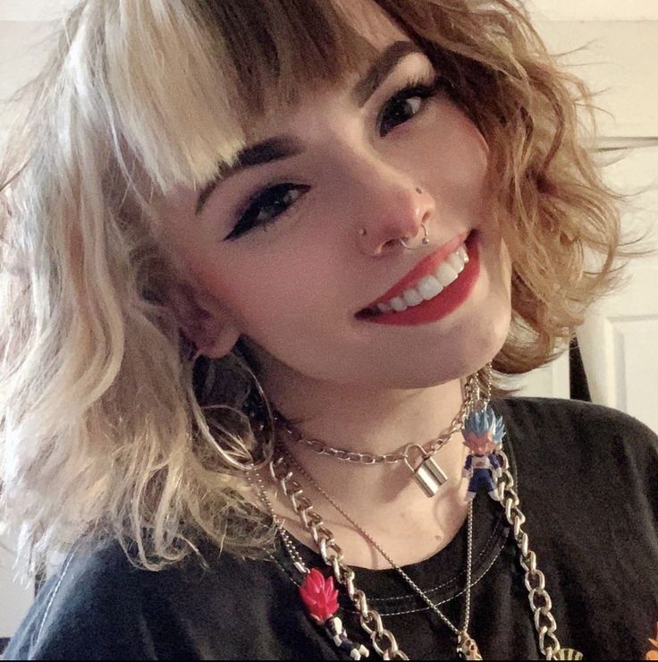 a close up of a person wearing necklaces and piercings on her face with a smile