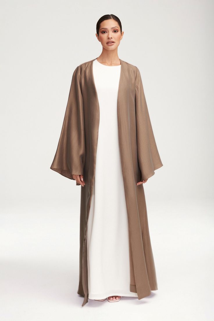 Transform any outfit into a statement with our Seema Flare Sleeve Open Abaya in Taupe. Its luxurious fabric boasts a subtle sheen, while the dramatic flare sleeves add a touch of artful elegance. Step out in style and sophistication with this exclusive piece. Model is 5'7" and is wearing size XS/58". Abaya Inspiration, Abaya Outfit, Moslem Fashion, Open Abaya, Hijab Trends, Muslim Women Fashion, Flowy Design, Satin Long Sleeve, Flare Sleeves