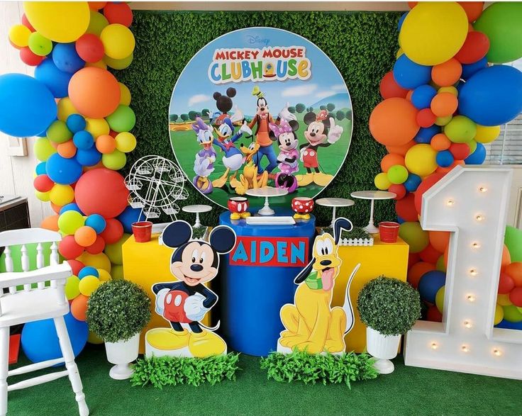 a mickey mouse birthday party with balloons and decorations on the wall, including an ice cream stand