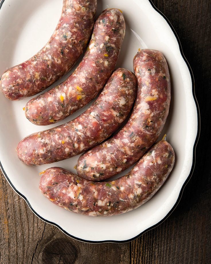 several sausages in a white bowl on a wooden table