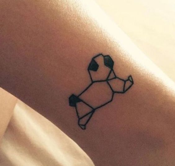 a small tattoo on the leg of a woman's lower arm, with an origami dog