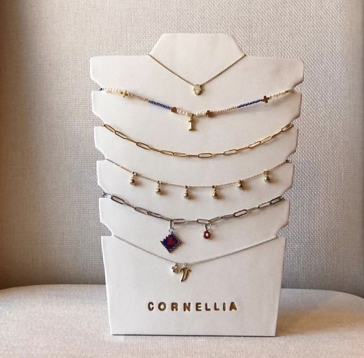 a display case with different types of necklaces on it's sides and the words corneilia written in gold