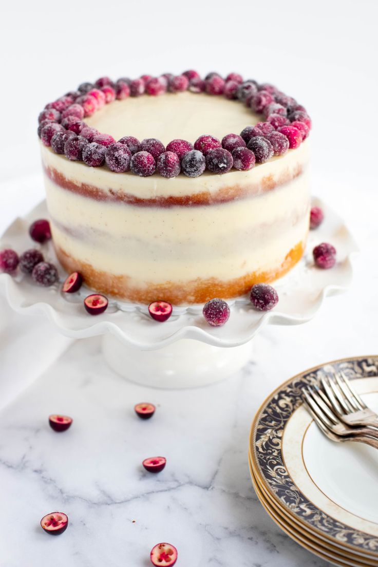 there is a cake with berries on the top and white frosting, sitting on a plate