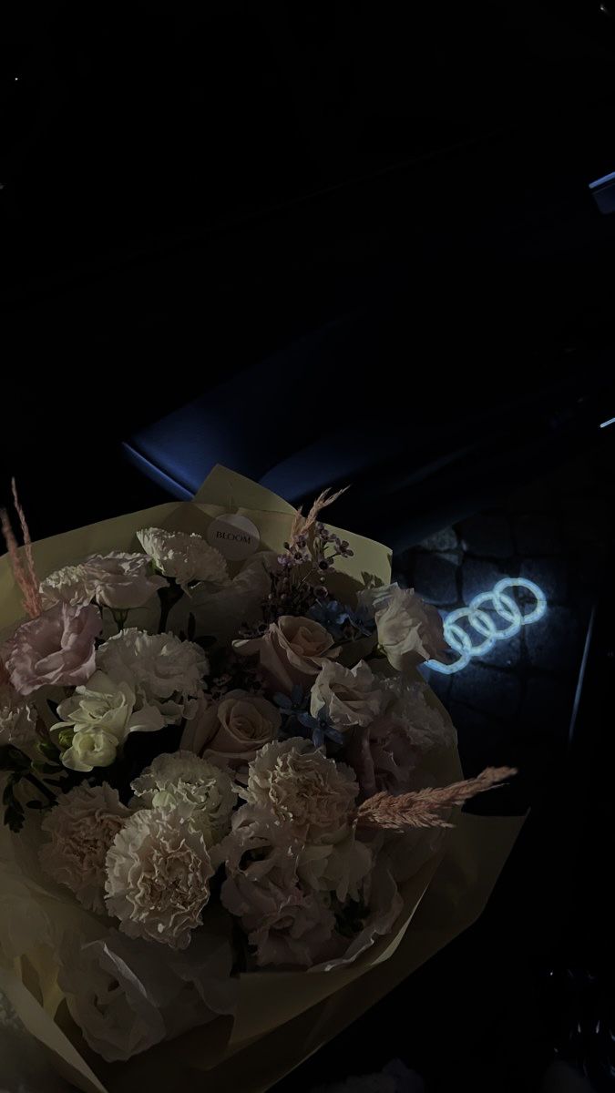 a bouquet of flowers sitting on top of a table in front of a neon sign