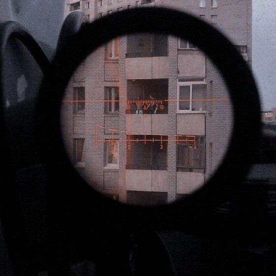 looking through a magnifying glass at an apartment building in the distance with lights on