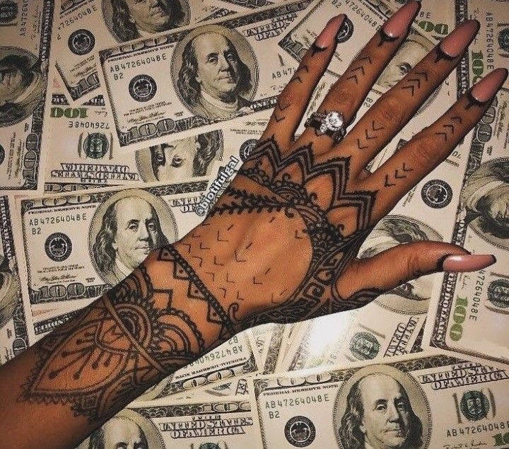 a person's hand with tattoos on it and money in the background, all around them