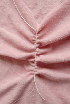 the back of a pink shirt that has been stitched together with two white pins