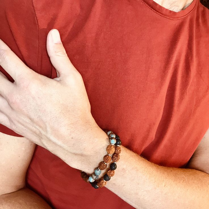 The Rudram Wrist Mala was designed to reflect earth colors . The combination of Lava Rocks, Rudraksha seeds and tiny silver Hematite beads are a winning of choice of earth colors and grounding energy. - Lava Rock is known to be a grounding stone that strengthens one's connection to Mother Earth. It activates courage and provides stability through times of change. - Rudraksha is the seed of a broad-leafed evergreen tree found mainly in the Himalayan foothills. It is believed that wearing these be Meditation Bracelets With Natural Lava Stones, Holistic Brown Bracelets For Meditation, Spiritual Brown Beaded Bracelets For Everyday, Minimalist Gemstone Beaded Bracelets For Meditation, Spiritual Brown Beaded Bracelets, Hand Wrapped Brown Beaded Bracelets For Meditation, Brown Natural Stones Bracelet For Meditation, Brown Gemstone Beads Bracelets For Meditation, Hand-strung Brown Beaded Bracelets For Meditation