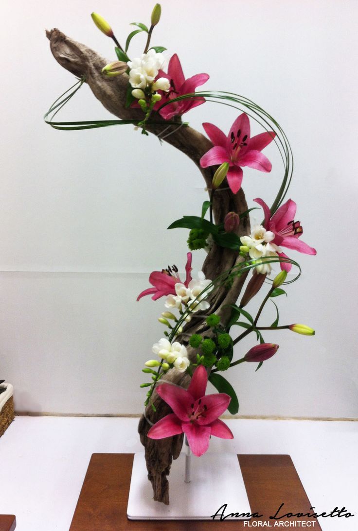 an arrangement of flowers in a vase on a wooden stand with white and pink flowers