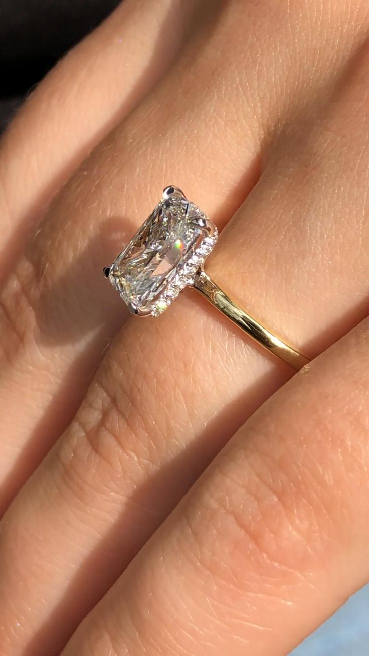 a woman's hand with a diamond ring on top of her finger and an engagement band