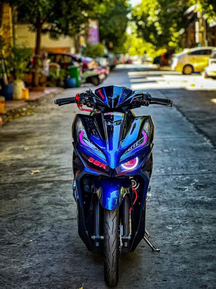 a blue motorcycle parked on the side of a road next to a tree lined street