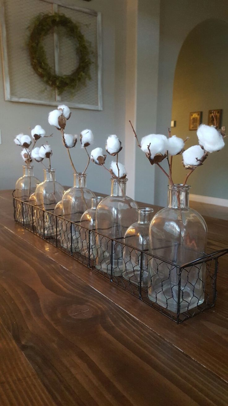 several vases with cotton flowers in them on a table