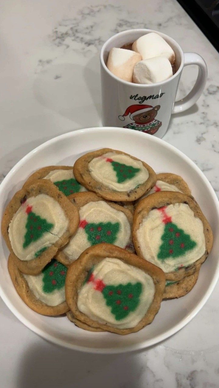 some cookies and marshmallows are on a plate next to a cup of coffee