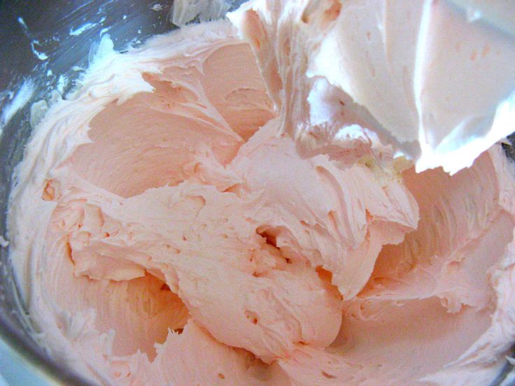 a bowl filled with pink frosting next to a spoon