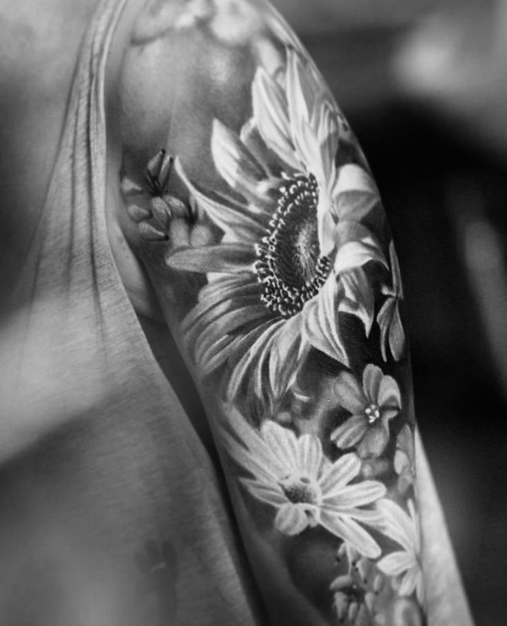 a black and white photo of a man's arm with sunflowers on it