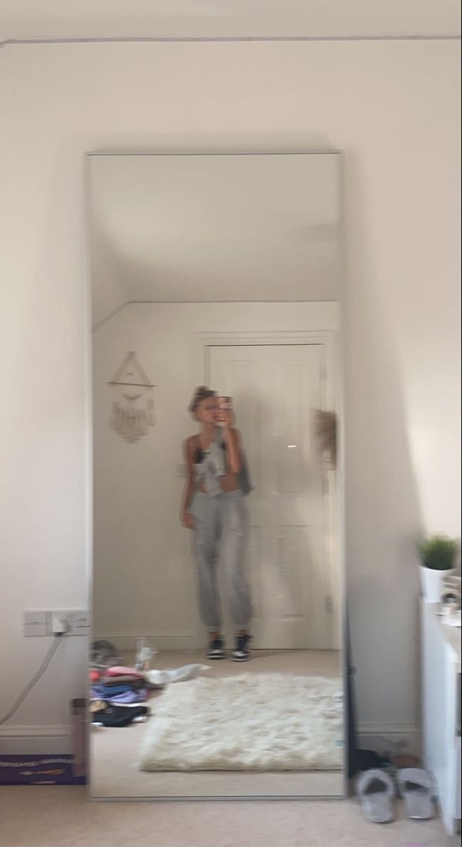 a woman taking a selfie in front of a mirror with her reflection on the wall