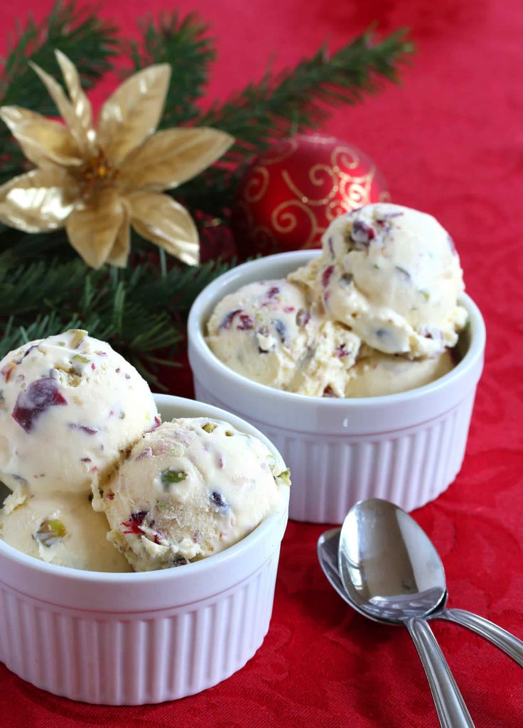 two white bowls filled with ice cream next to a christmas ornament and spoon