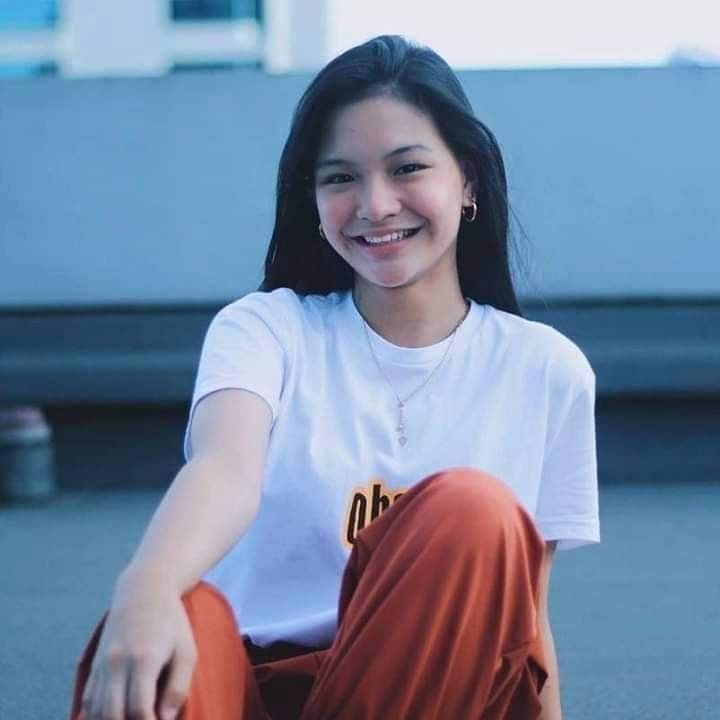 a young woman sitting on the ground smiling