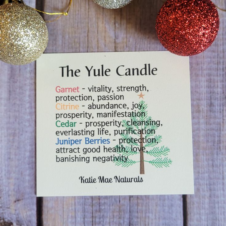 the yule candle is next to two christmas ornaments on a wooden table with a card