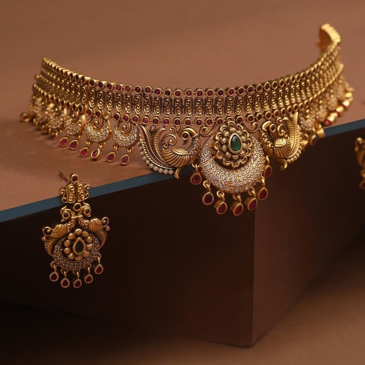 Description Pure and refined, this beautiful choker set by Tarinika is timeless elegance. It defines high quality craftsmanship and is thoughtfully designed to create a beautiful pattern. Peacock motifs add the element of nature to this masterpiece. Wear this with a gorgeous saree to make a beautiful impression. Details & Specifications: Materials used: Brass Alloy with Antique Plating Weight – Necklace 63 gm, Earrings 14 gm Length – Necklace 21 cm, Earrings 4.5 cm Make it custom Want to make it Pure Gold Choker Necklace Set, Rajputana Jewellery, Manubhai Jewellers, Choker Design, Rajputi Jewellery, Bridal Necklace Designs, Gold Jewels Design, Neck Pieces Jewelry, Antique Necklaces Design