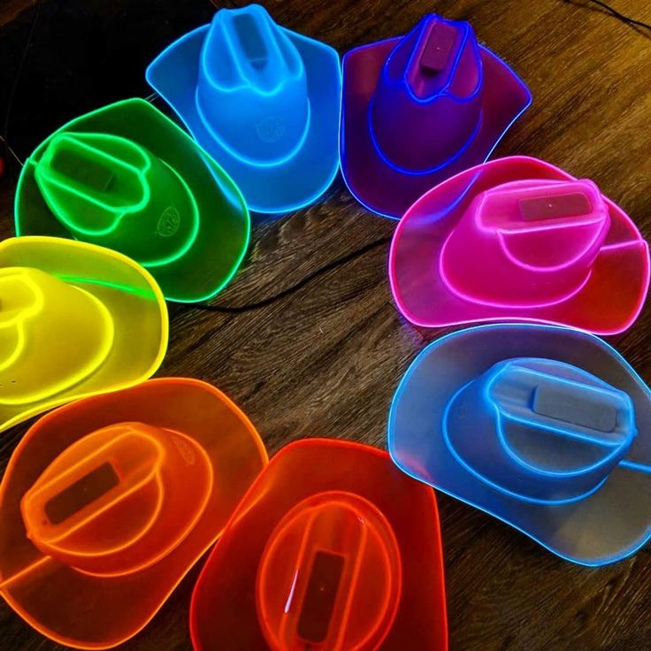 there are many different colors of plastic bowls on the table with spoons in them