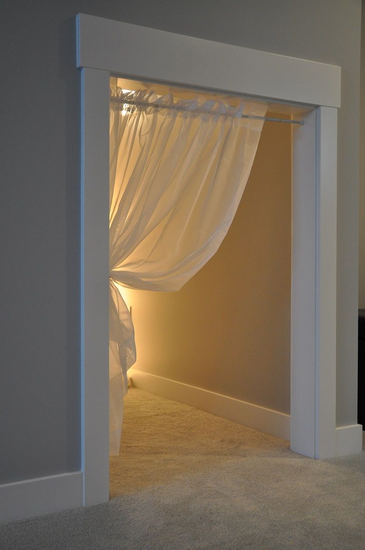 an open door leading to a bedroom with white drapes on the walls and carpeted floor