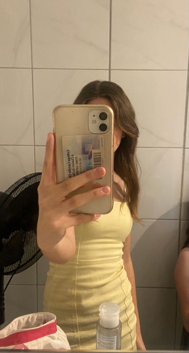 a woman taking a selfie in front of a bathroom mirror with her cell phone