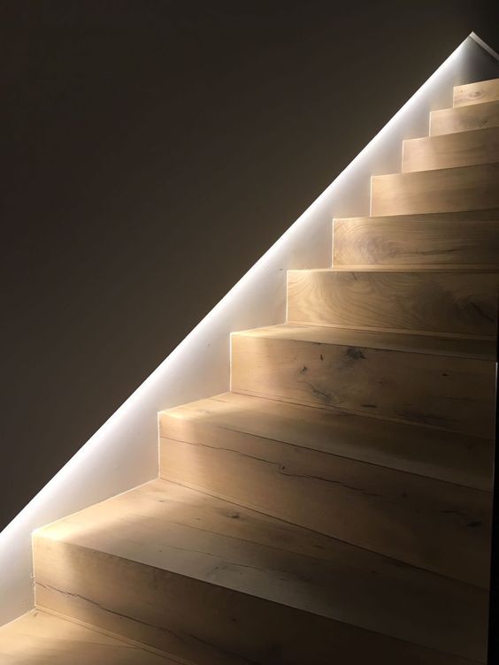 an illuminated stair case with wooden steps and white lighting on the bottom part of it