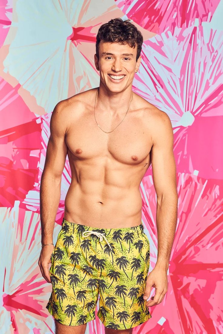 a shirtless man standing in front of a colorful wall with palm trees on it