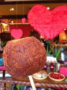 a heart shaped lollipop sitting on top of a stick in front of a store