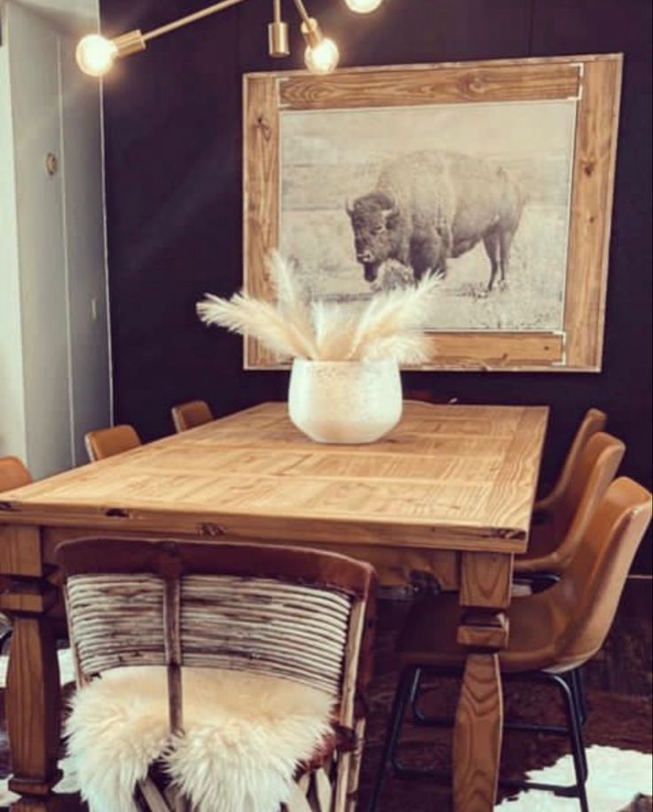 a dining room table with chairs and a cow print on the wall