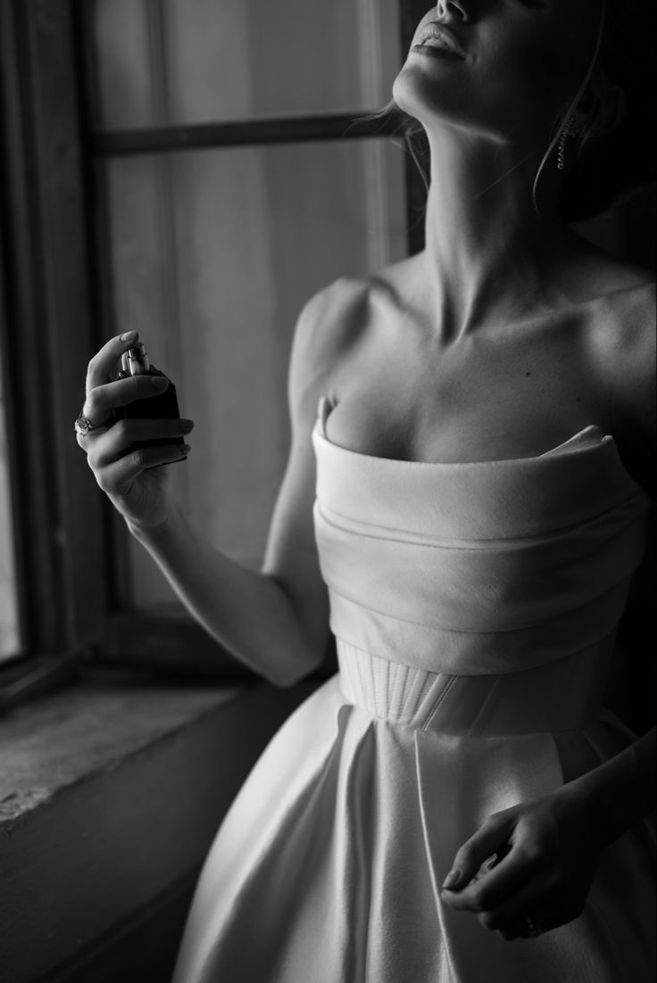 black and white photograph of a woman in a dress holding a ring on her finger