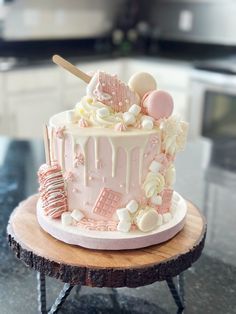 a pink and white cake sitting on top of a wooden table next to a counter