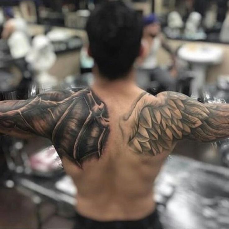 the back of a man's upper half with wings on his arm and chest