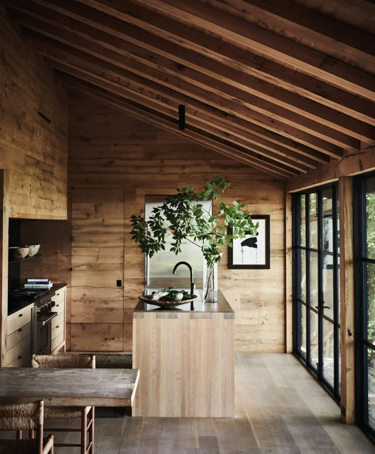 a kitchen with wooden walls and flooring next to windows