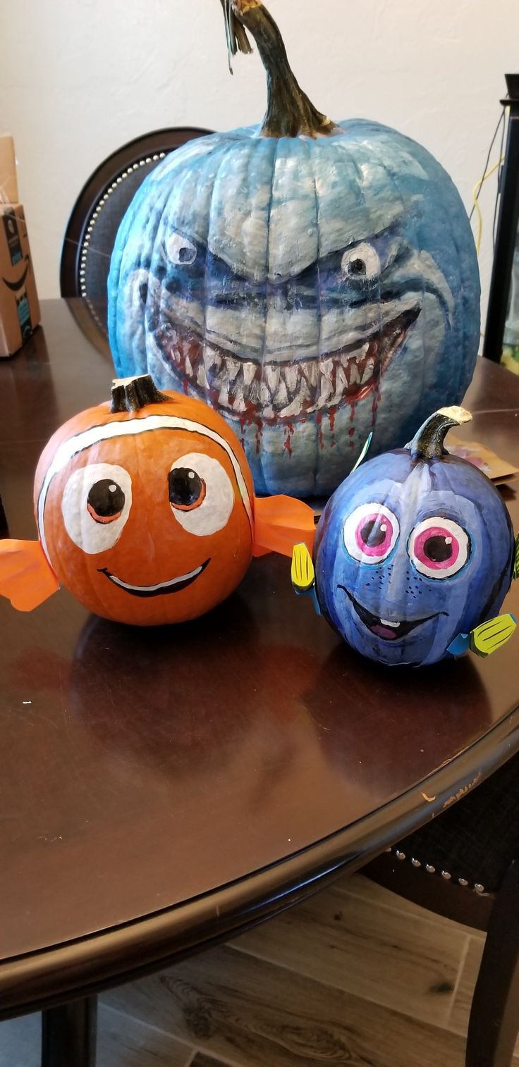 three pumpkins with faces painted on them sitting on a table next to each other