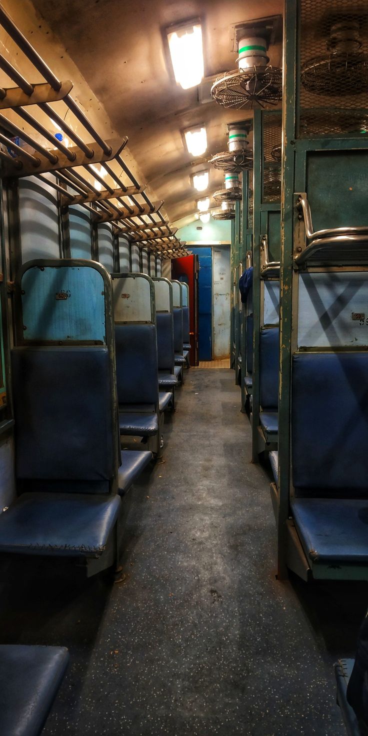 an empty train car with blue seats and lights on the ceiling is seen in this image